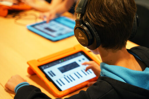 Kind met koptelefoon op Ipad met muziekprogramma